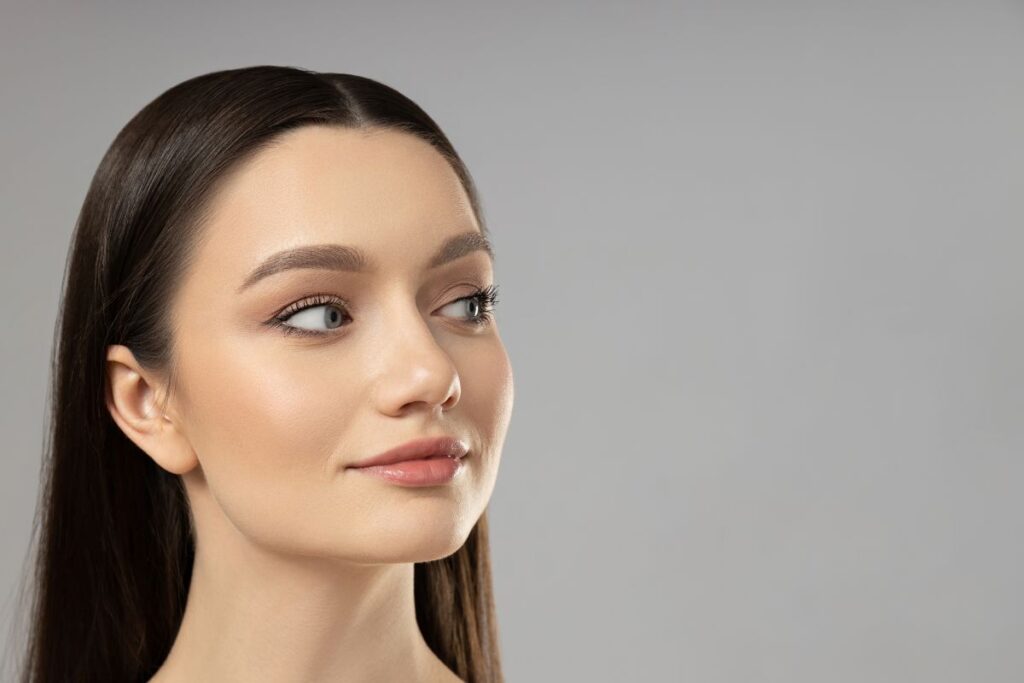 Young woman with smooth, glowing skin looking to the side, ideal candidate for preventative Botox in her 20s.