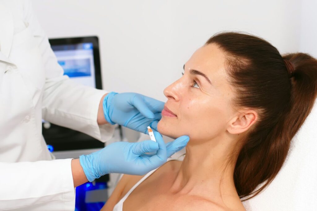 Woman receiving Botox injection from doctor wearing blue gloves, aiming to reduce early aging signs in her 30s.