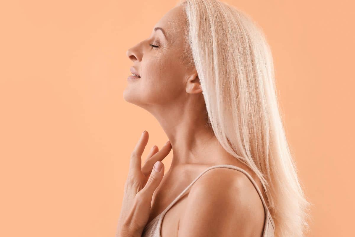 Mature woman with smooth jawline and firm neck skin, representing results of a surgical neck lift compared to alternatives.