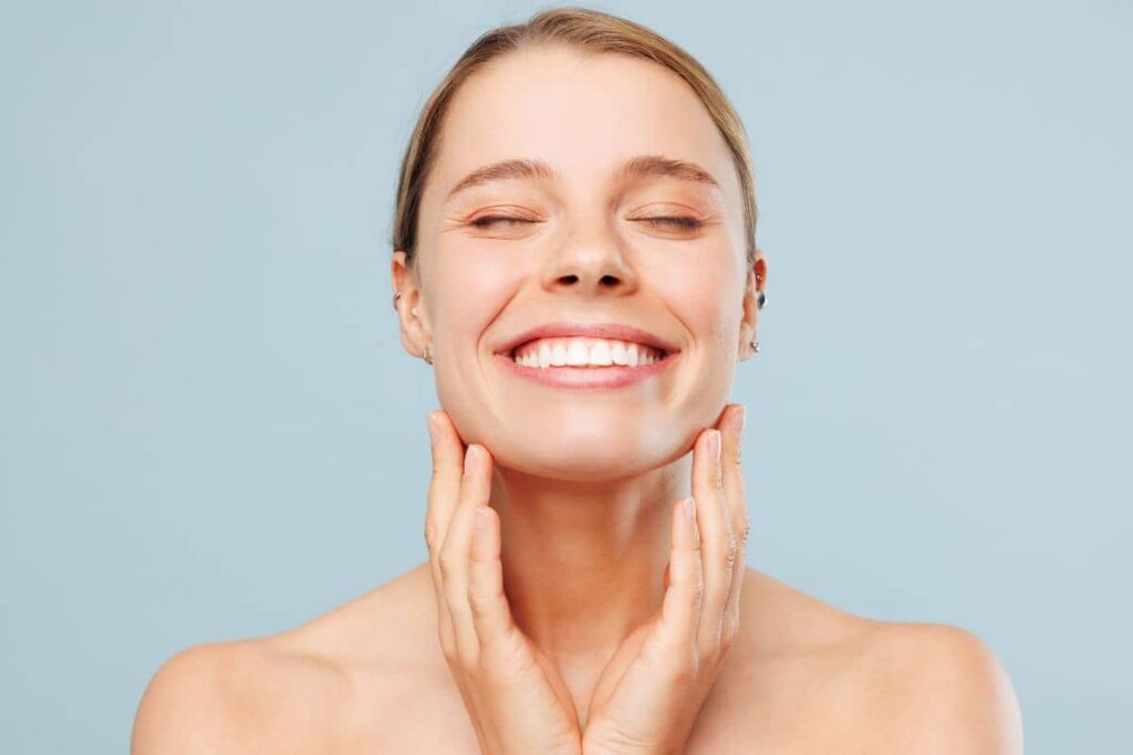 Smiling woman gently touching her neck, symbolizing confidence after selecting the right neck rejuvenation treatment.