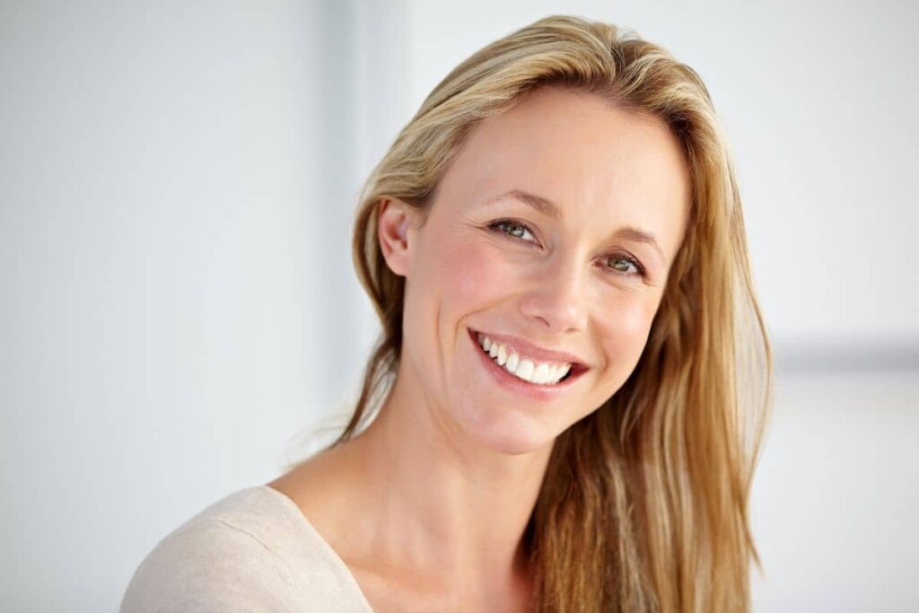 Happy woman with smooth skin and defined jawline, showing natural results after a mini facelift procedure.