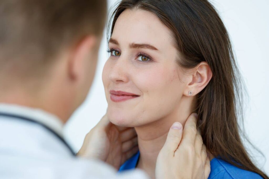 Facial plastic surgeon examining patient’s neck during consultation about neck lift surgery and recovery time